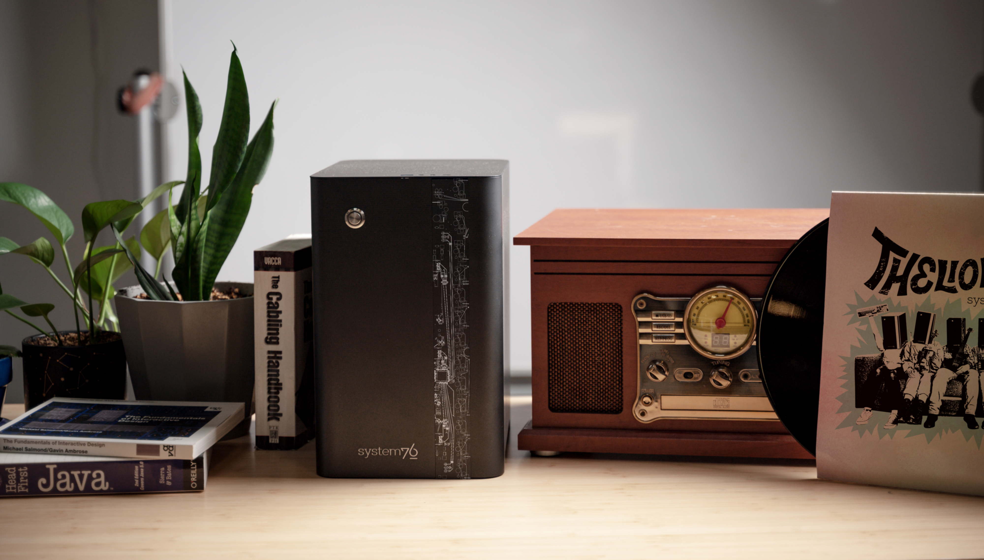 Thelio prime site on a desk next to a vinyl record player, showing how small it is in comparison
